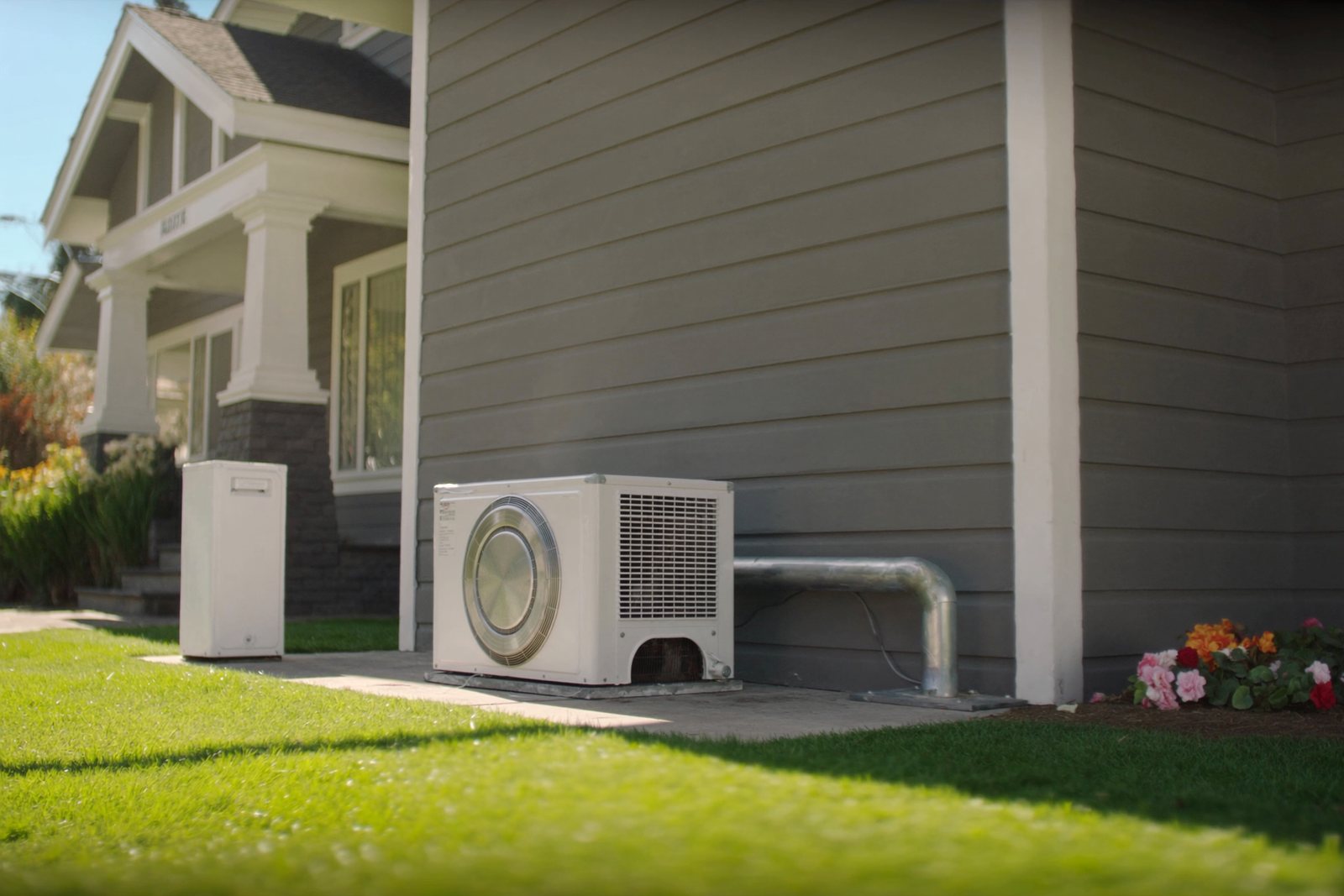 A heat pump beside a painted bungalow in morning sun